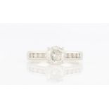 A hallmarked 18ct white gold diamond ring, set with a principle round brilliant cut diamond