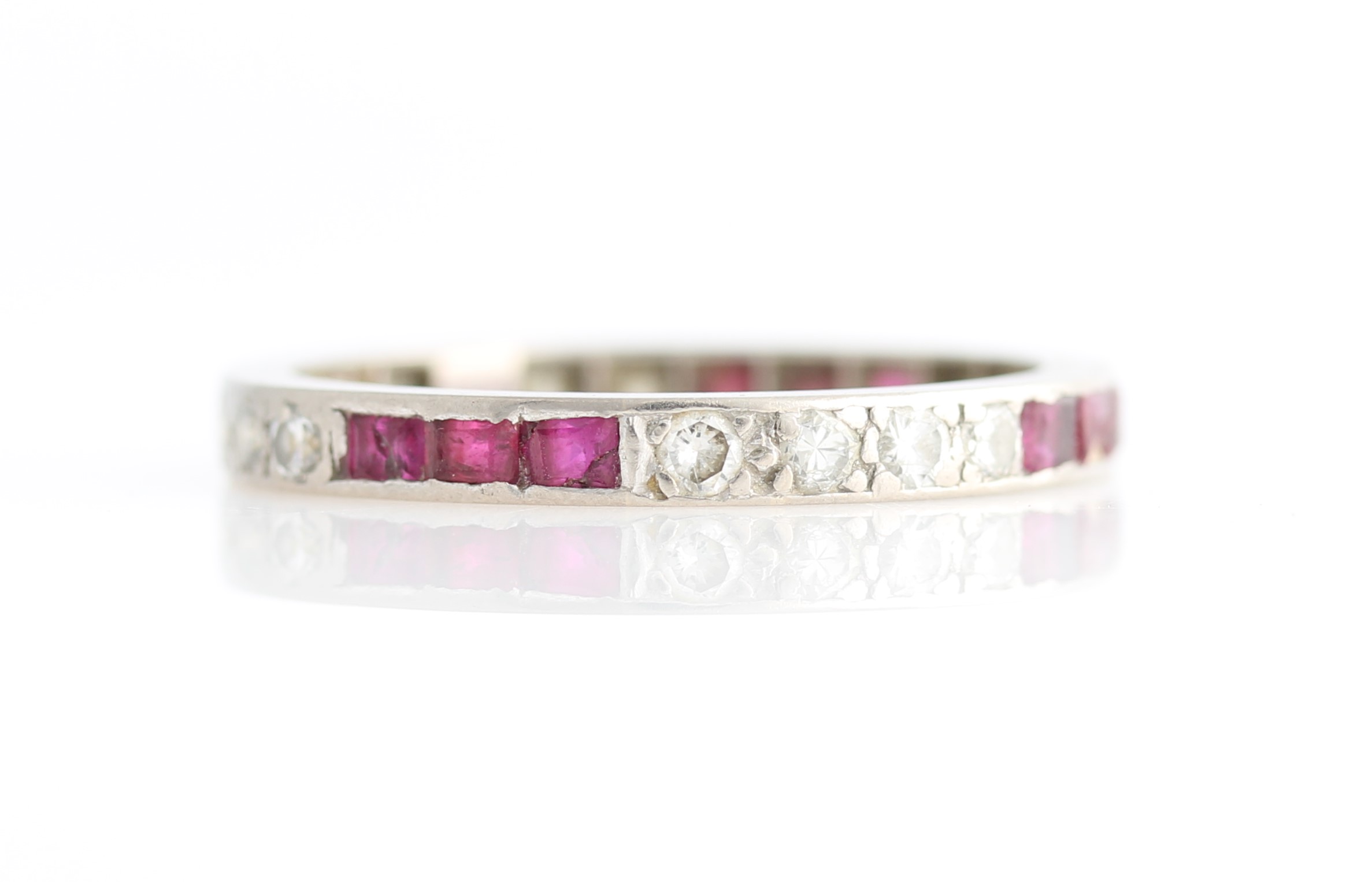 A ruby and diamond full eternity ring, set alternately with three square cut rubies and two sets of