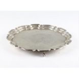 A silver salver, the circular form with pie crust rim and central personal engraving, raised on
