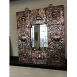 An copper, hand beaten, arts and crafts wall mirror with four female faces to corners.