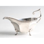 A silver Walker & Hall sauce boat, with stylised scroll design handle and raised on three hoof feet,