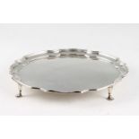 A silver salver, featuring pie crust rim and raised on four hoof feet, hallmarked Sheffield 1966,
