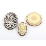 Three pin cushions comprising an oval 19th Century ivory example one side well carved with a bouquet