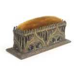 A Victorian brass sewing weight/pin cushion modelled as a Gothic tomb, the decoration to three