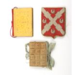 Three needle books comprising a petit point example as a heraldic shield, ivory silk interior,