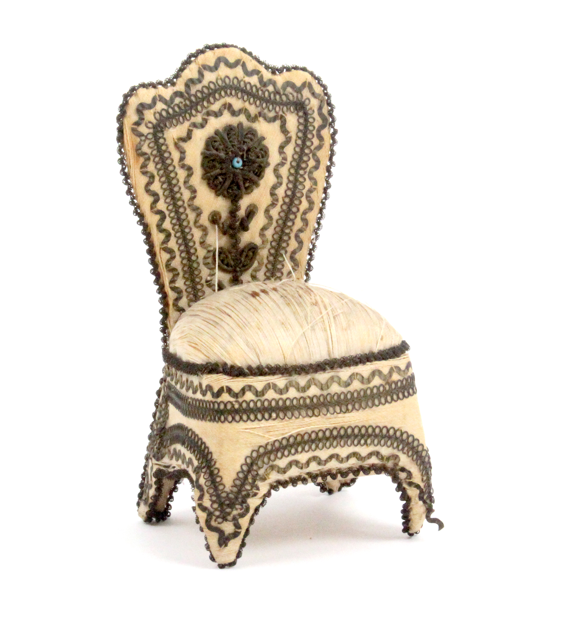 An ivory silk pin cushion in the form of a chair with coiled wire borders and metal appliques, the