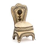 An ivory silk pin cushion in the form of a chair with coiled wire borders and metal appliques, the