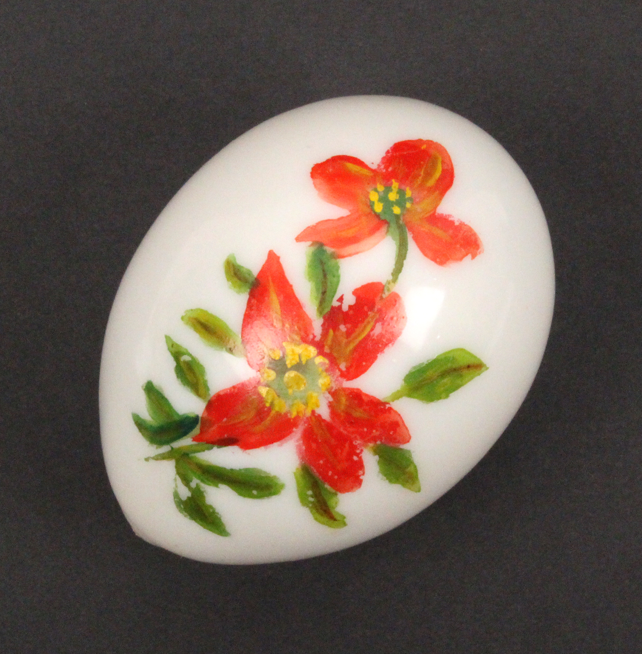 An opaque glass egg form hand cooler painted with a flowering branch, 8.5cm