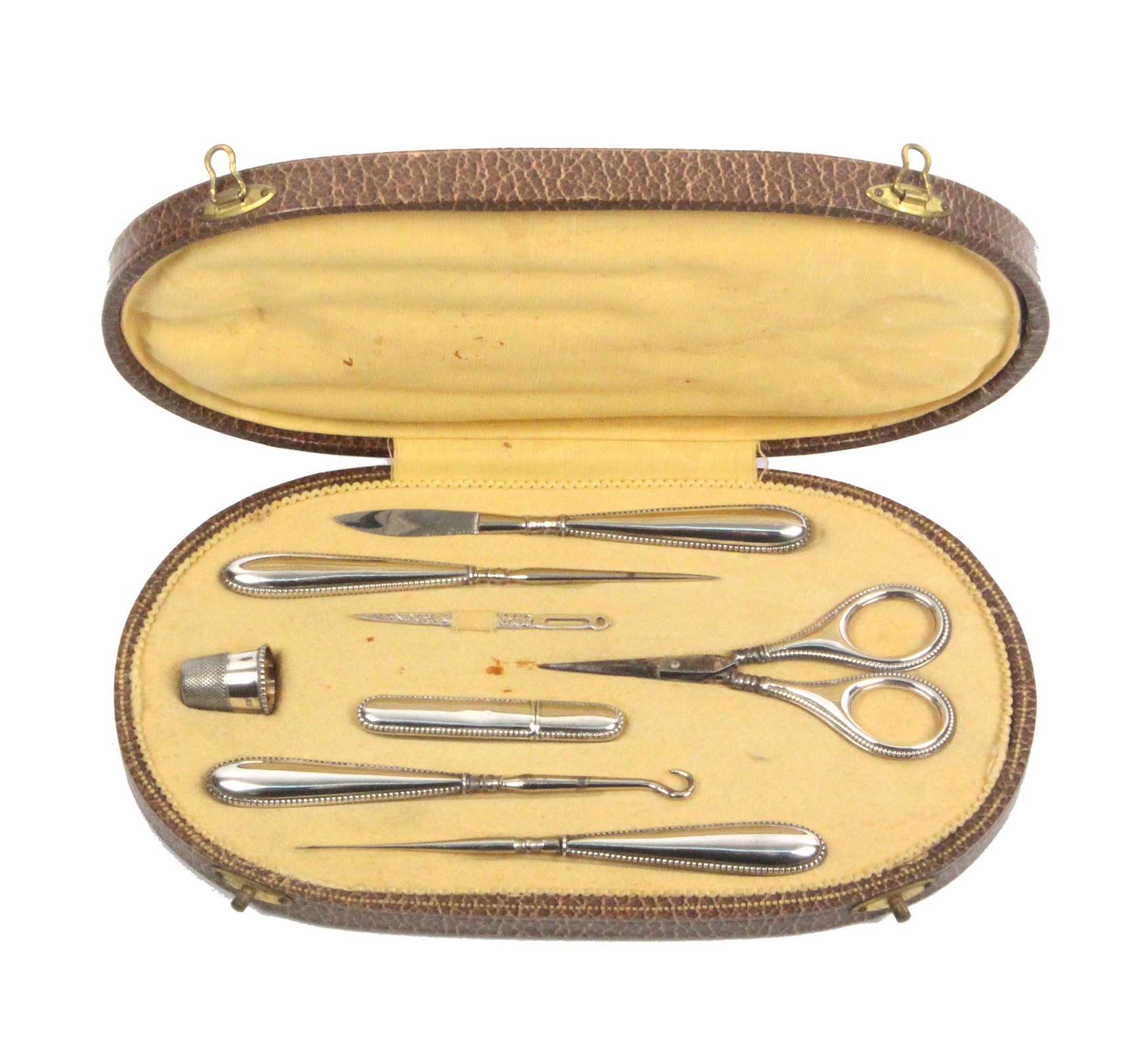 An early 20th Century continental sewing companion, the oval case covered in brown paper to simulate