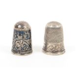Two silver thimbles comprising a Russian niello decorated example with Cyrillic script over a leaf