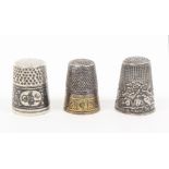 Three thimbles comprising a silver example the floral niello frieze with oval panels one engraved