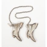 A pair of silver continental knitting needle protectors each modelled as a lady's boot, linked by