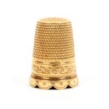 A 19th Century gold thimble in leather case, the frieze with scroll engraving over a scallop form