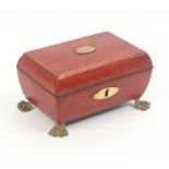 A Regency red leather sewing box for a child, of sarcophagal form with oval gilt escutcheon and