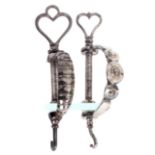 Two early 19th Century cut steel clamps, each with a decorative curved frame and supporting a