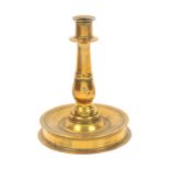 A 17th Century brass candlestick, on circular base tapering downward to the stem, 20cm high, 15cm