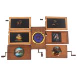 Seven mechanical magic lantern slides in wooden frames comprising three rotating circular slides -