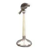 A silver pin cushion in the form of a parrot perched on a mother of pearl pedestal on a circular