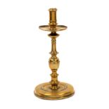 A 17th Century brass candlestick, domed circular base to a turned stem with broad drip pan, 25cm