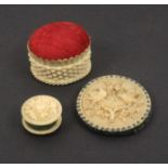 Two good ivory pin cushions and a waxer, comprising an oval basket form pin cushion, 4.2cm., another