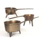 Three 18th Century bell metal skillets, the largest with handle cast 'Thomas ++++', the body cast