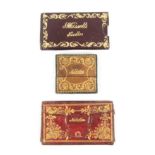 Three unusual leather needle cases comprising a rectangular maroon leather example tilted in gilt to