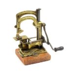 A child's sewing machine 'The Tabitha' decorative gilt metal frame on plain wooden base, 11cm wide