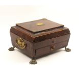 A Regency sewing box of sarcophagal form covered in diced brown leather with gilt metal mounts on