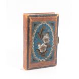A mid Victorian skein book bound in leather, the cover with an inset coloured beadwork floral panel,