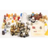 A collection of thimbles including brass, plastic, aluminium and brass advertising, glass,