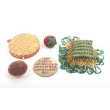 Five pin cushions comprising an embroidered circular pierced card example, 6.7cm dia, a geometric