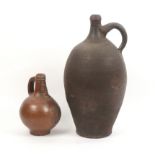 A 17th or 18th Century salt glazed Bellarmine jug and another, the first with bearded mask over an