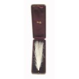 An Edwardian leather cased hair ornament, the rectangular red leather case velvet and silk lined and