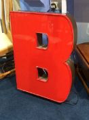 A large red neon sign of the letter 'B'