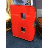 A large red neon sign of the letter 'B'