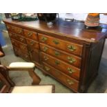 An antique oak dresser base with hinged top, three dummy drawers, above seven drawers and a