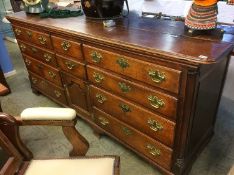 An antique oak dresser base with hinged top, three dummy drawers, above seven drawers and a