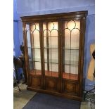 A walnut reproduction three door display cabinet