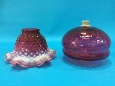 A cranberry coloured glass reservoir and a cranberry and milk glass shade