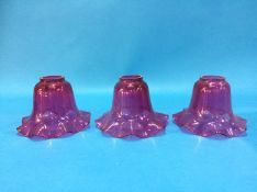 A set of three cranberry glass shades