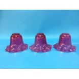 A set of three cranberry glass shades