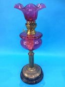 A Victorian oil lamp with cranberry reservoir and