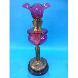 A Victorian oil lamp with cranberry reservoir and