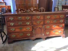 A Georgian oak dresser base with rising top, below two short drawers and a central cupboard door,