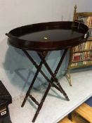 A reproduction mahogany oval butlers tray and stand