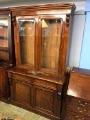 A Victorian mahogany glazed bookcase, below two drawers and two arched panelled doors, supported