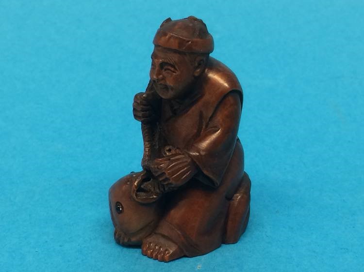 A carved wooden Netsuke in the form of a man catching a fish - Image 2 of 2