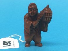 A carved wooden Netsuke in the form of a man holding a basket