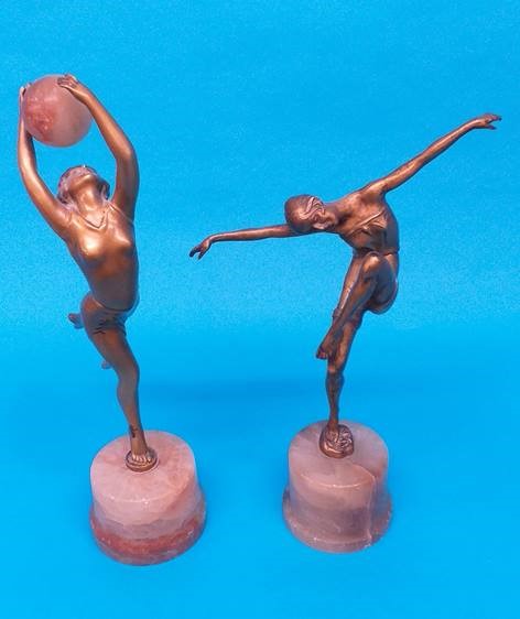 Two Art Deco spelter figures, one holding aloft an alabaster ball, the other with arms