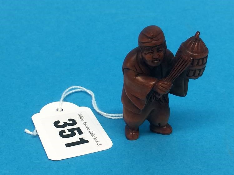 A carved wooden Netsuke in the form of a man holding a basket - Image 2 of 2